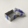 Caja regalo de color gris con lazo de color azul