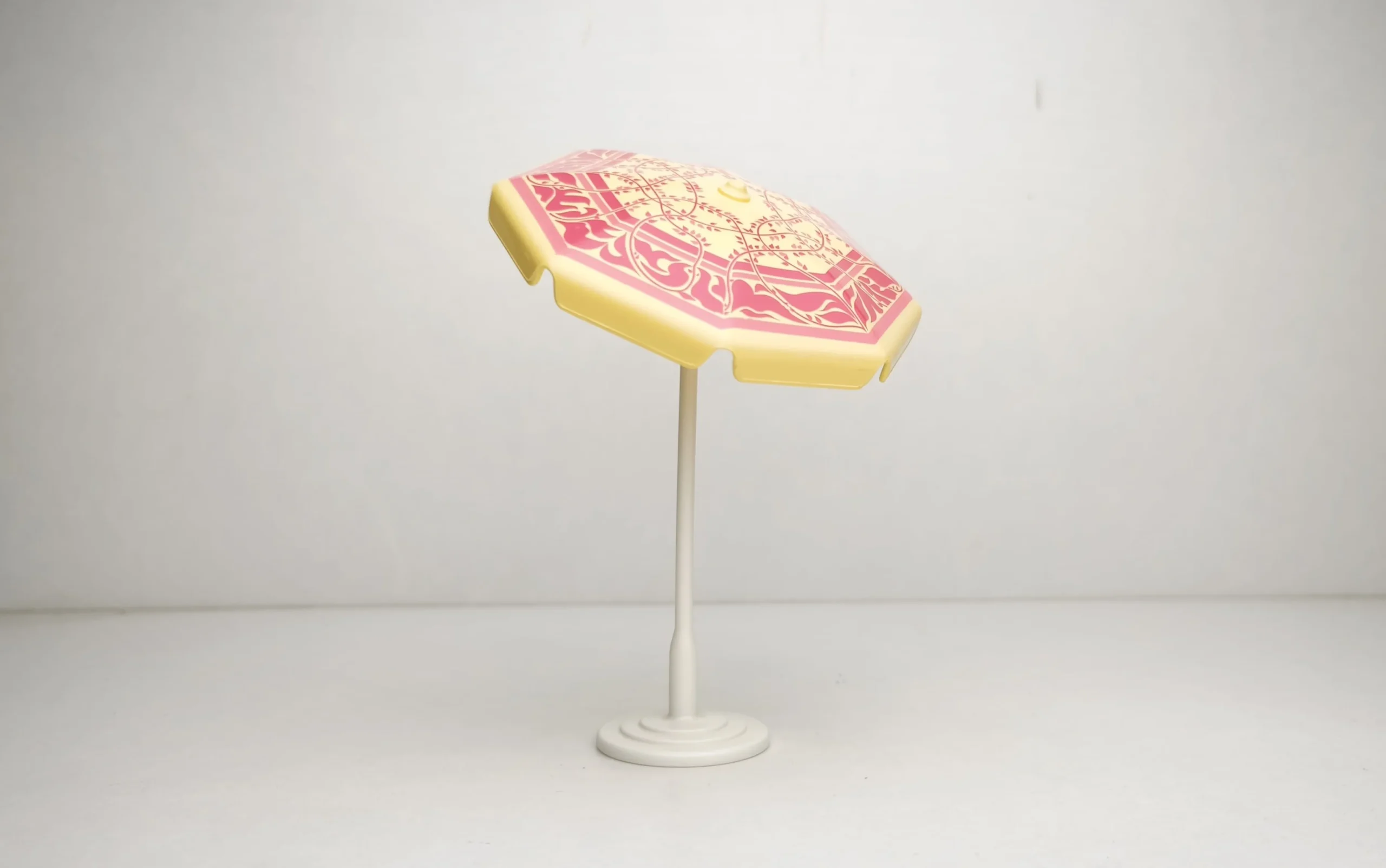 Sombrilla redonda de color amarillo con decoraciones en rosa
